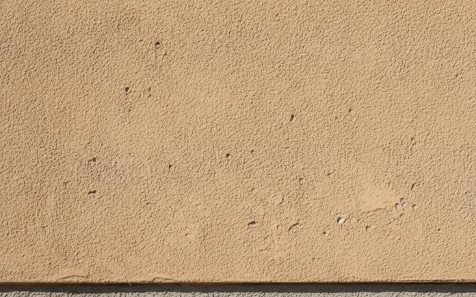 Close view of a stucco wall marked by hail impacts